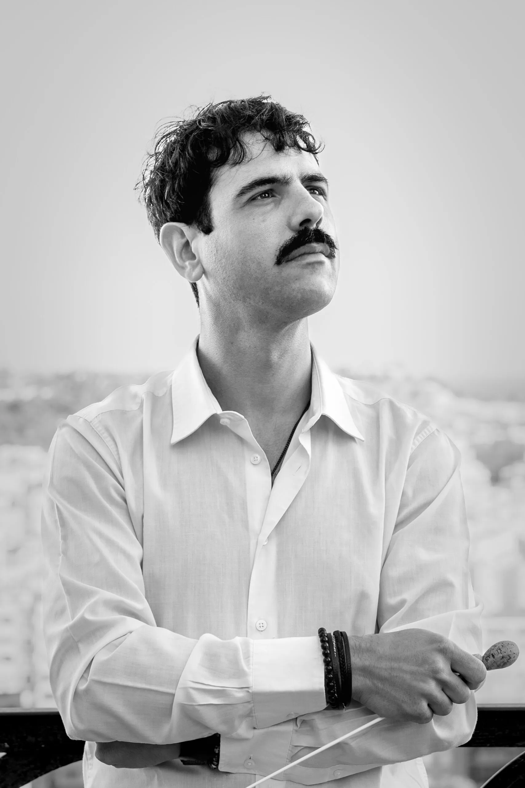 Portrait of Federico Bresciani looking into the distance, holding a conducting baton